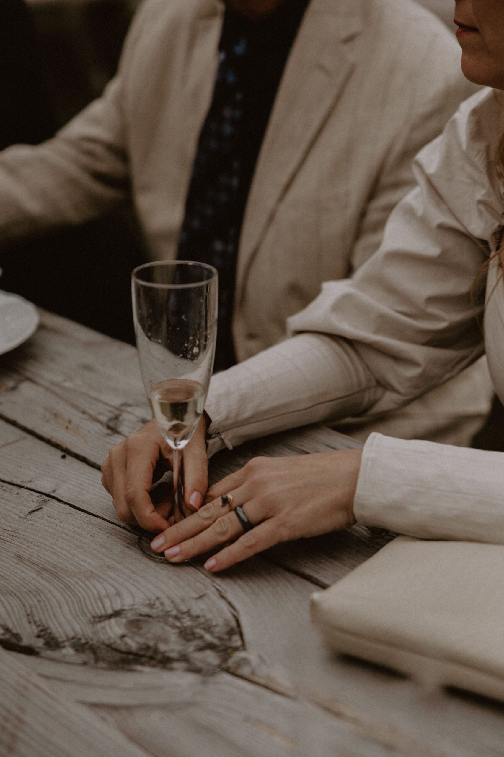 Champagneglas står på ett träbord en kvinna håller sina händer vid glasets fot