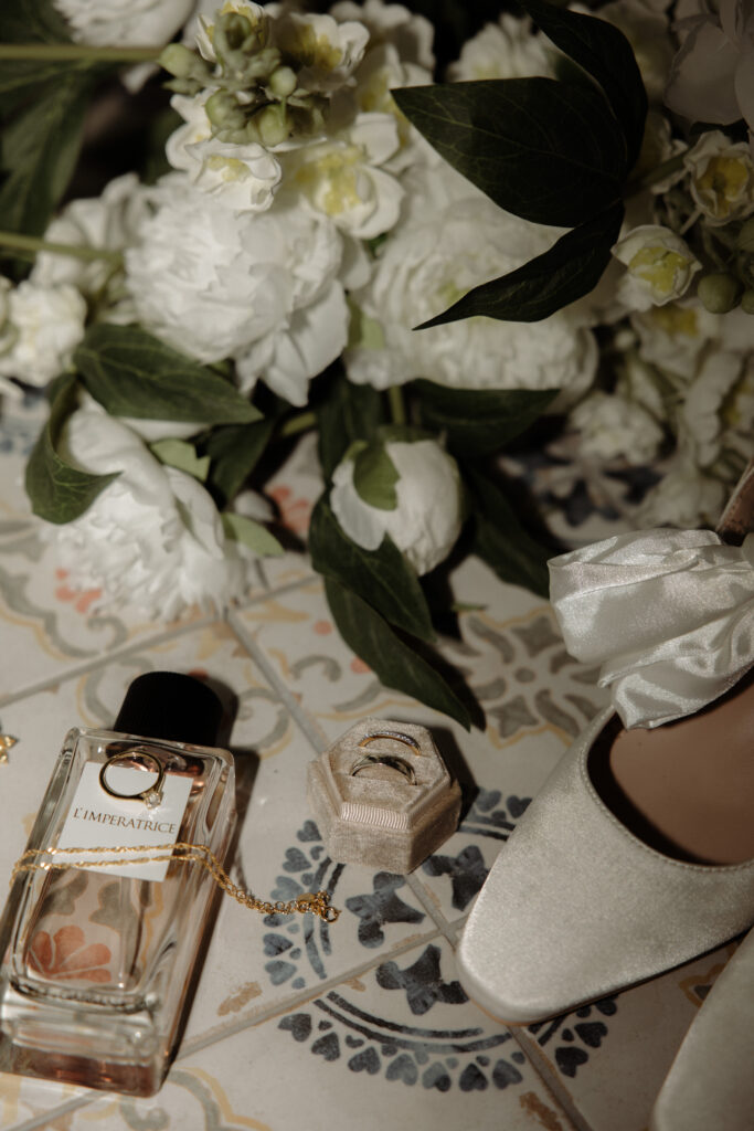 brudens skor, parfym, smycken, brudbukett och vigselringar liggandes på kakelgolv