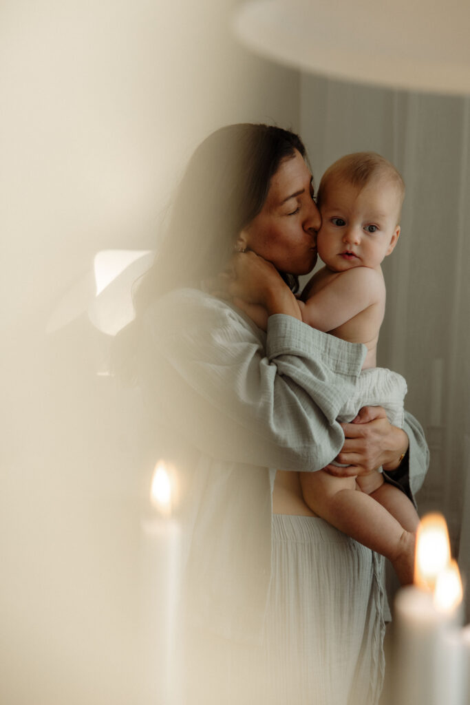 mamma håller om och pussar sin bebis i sin famn i vardagsrummet