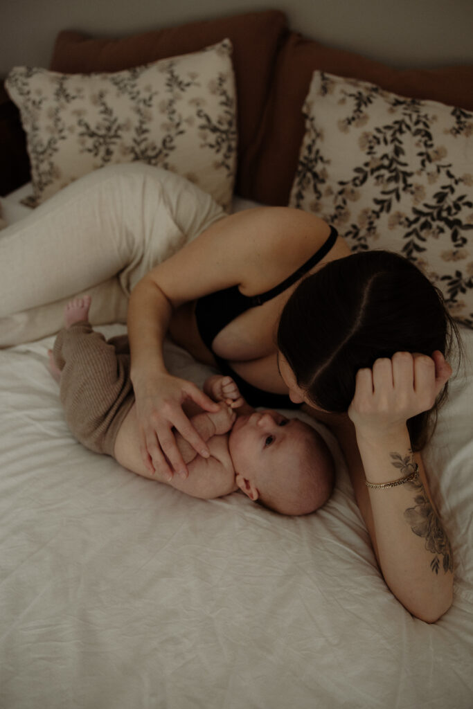 mamma och bebis ligger hemma i sin säng och gosar