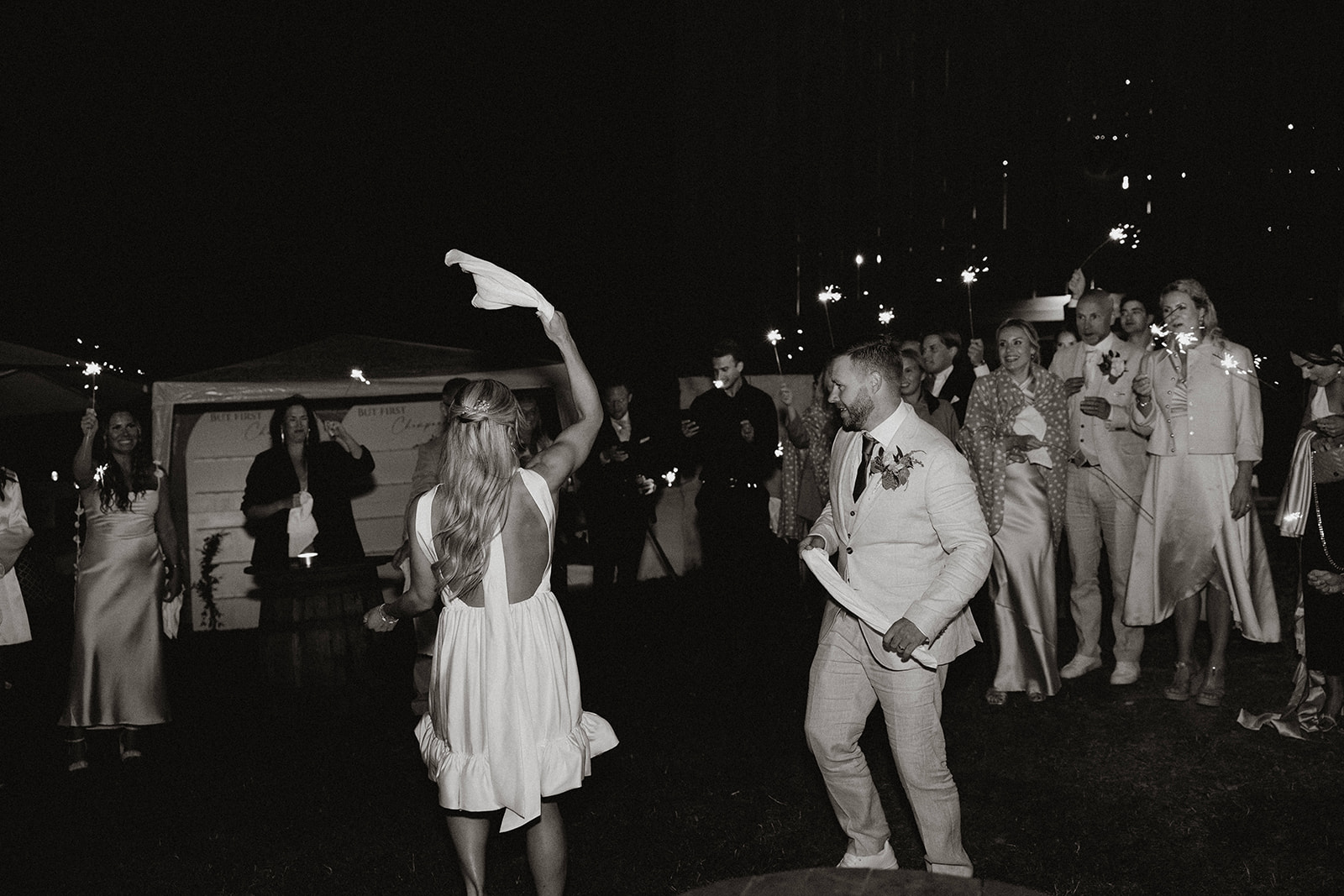 brudpar dansar med tomtebloss och bröllopsgäster